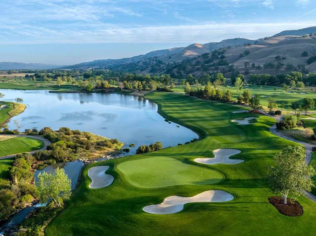 View of golf course with water and mountains